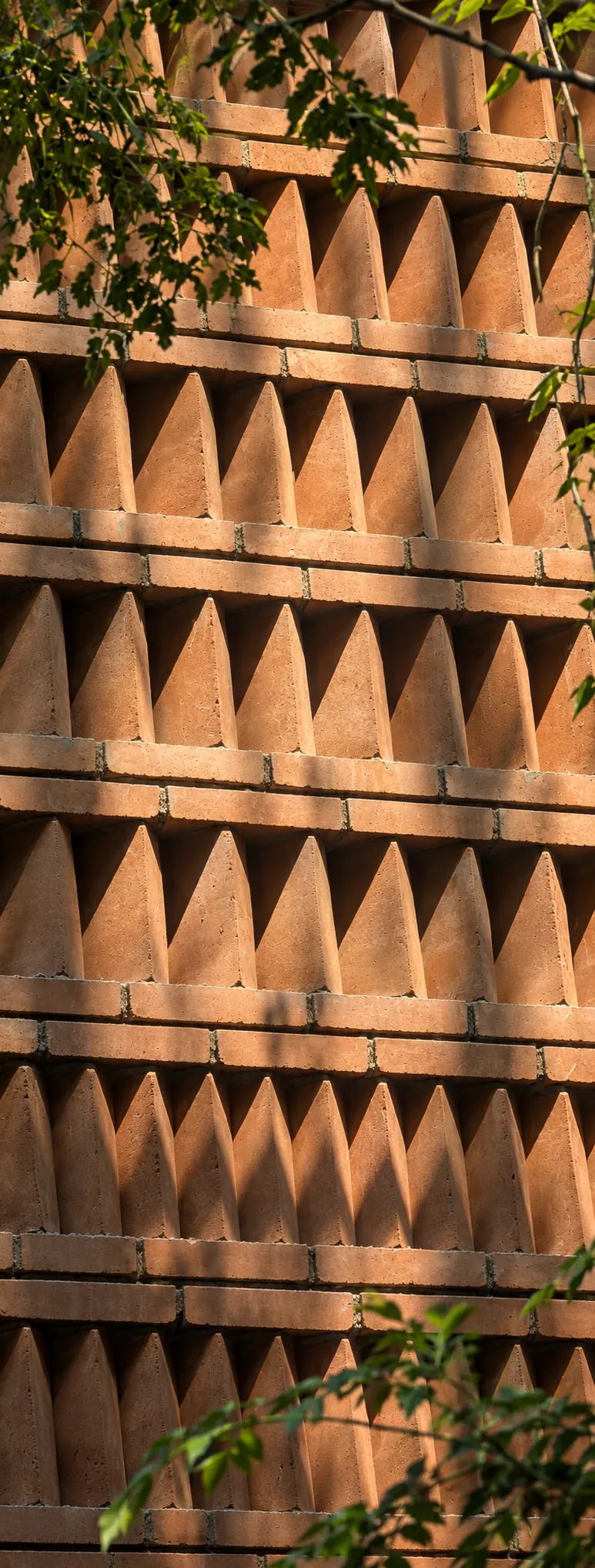 Anjanadri — a wall of interlocking earth blocks with pyramidal faces catching afternoon light